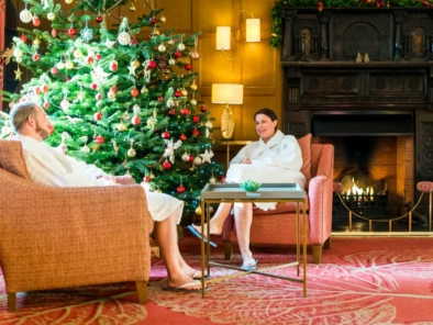 Guests relaxing by tree and open fire on Christmas spa break