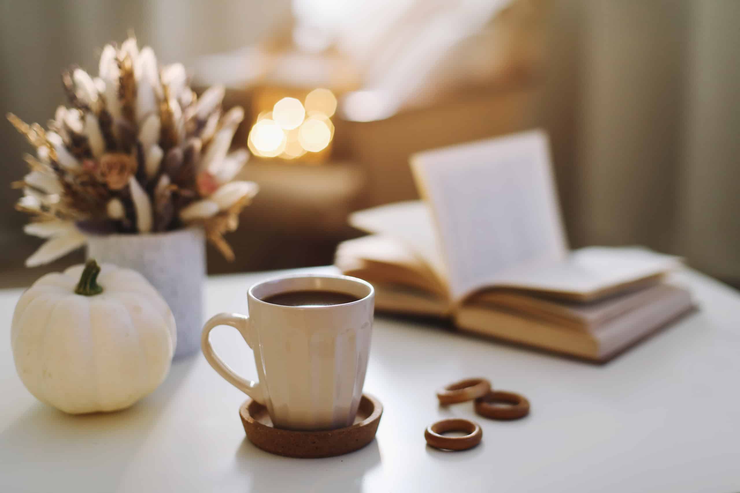 Autumn still life. Coffee cup, flowers, book and pumpkin. Hygge