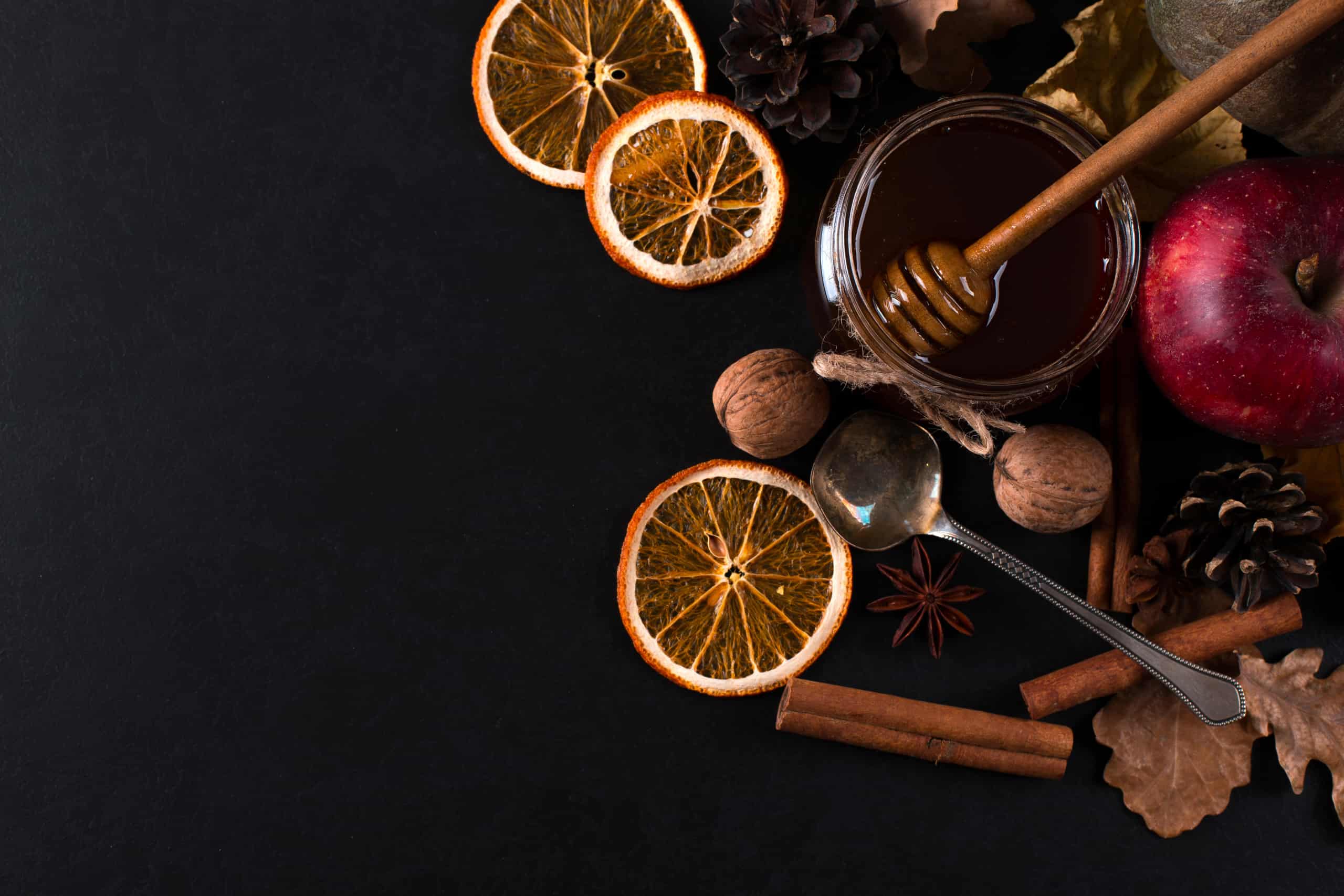 May liquid honey, fruits, cinnamon, dried oranges and nuts on a black background. autumn harvest, copy space.