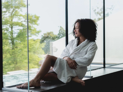 Woman looking out from a rooftop lounge in a robe